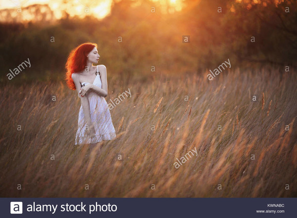 a-woman-with-red-curly-hair-in-white-sundress-on-background-of-dawn-KWNABC.jpg