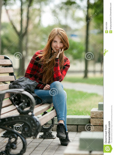 young-laughing-redhead-woman-red-plaid-jacket-blue-jeans-sitting-park-bench-blurred-park-background-lady-69514004.jpg